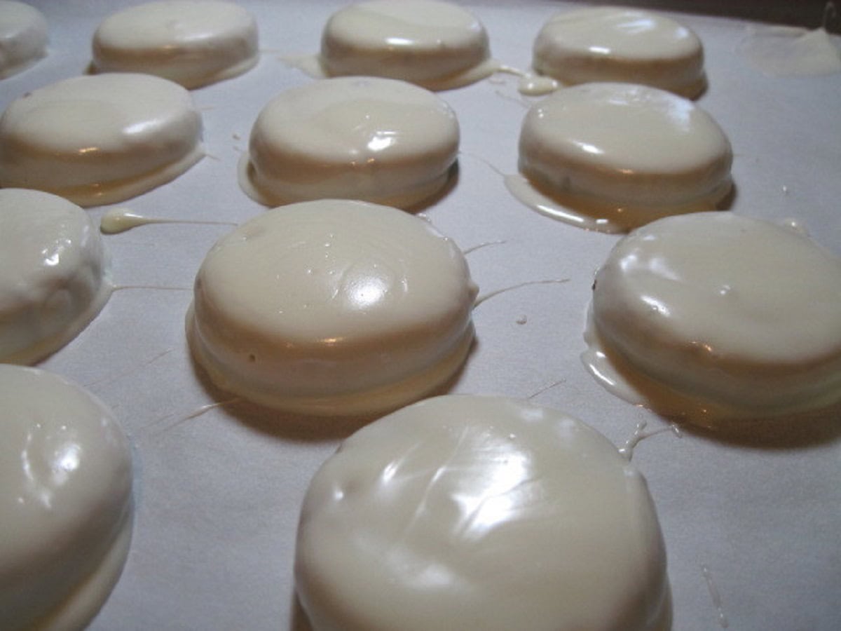 A bunch of white chocolate dipped cookies on a parchment lined baking sheet.