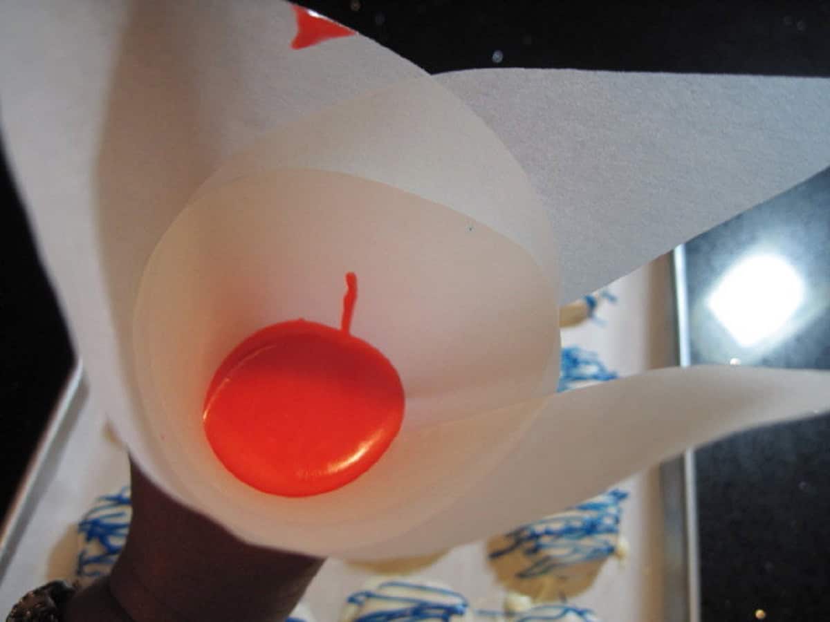 Red melted chocolate in a paper parchment cone.