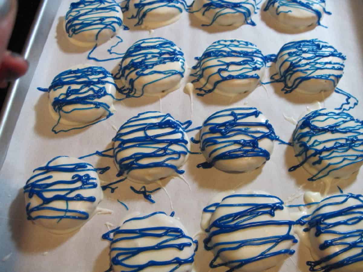 Blue squiggles of melted chocolate over a white chocolate dipped cookie.