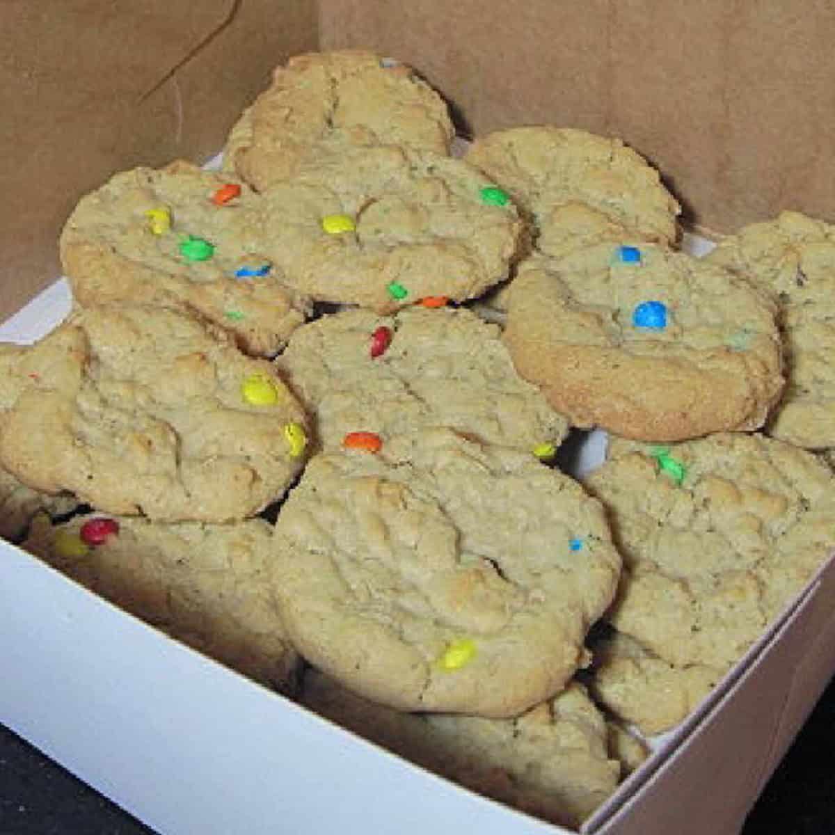 A bakery box filled with mini m and m oatmeal cookies.