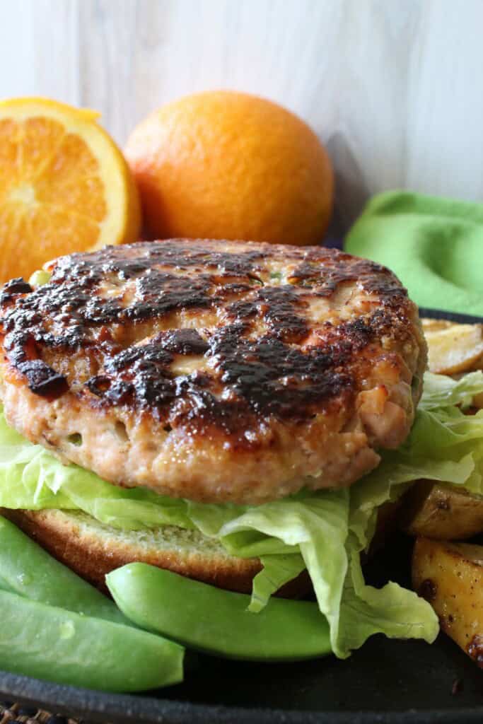 A naked Salmon Burger on a bun with lettuce.