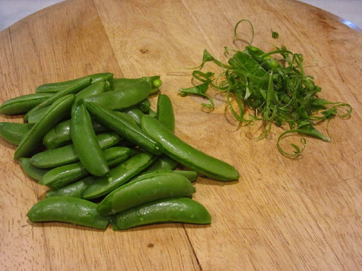 Sugar snap peas on a board after the strings have been removed.