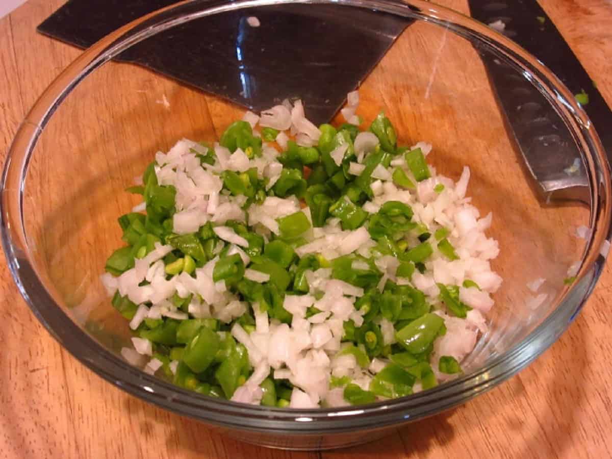 Minced shallots and chopped sugar snap peas in a glass bowl.