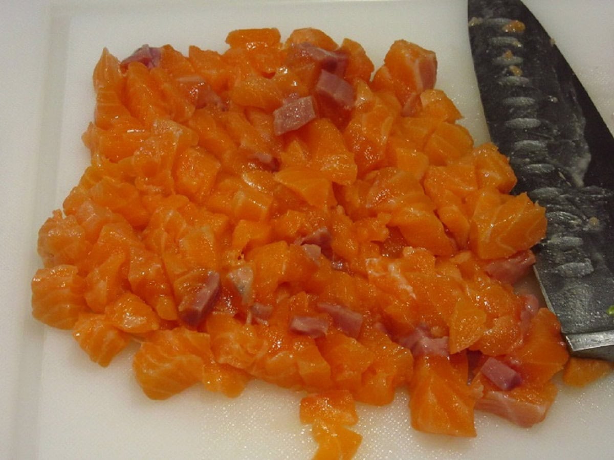 Diced salmon on a white cutting board.