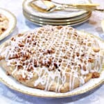 An apple Crumble Crostata on a pretty china plate with gold dessert forks in the background.