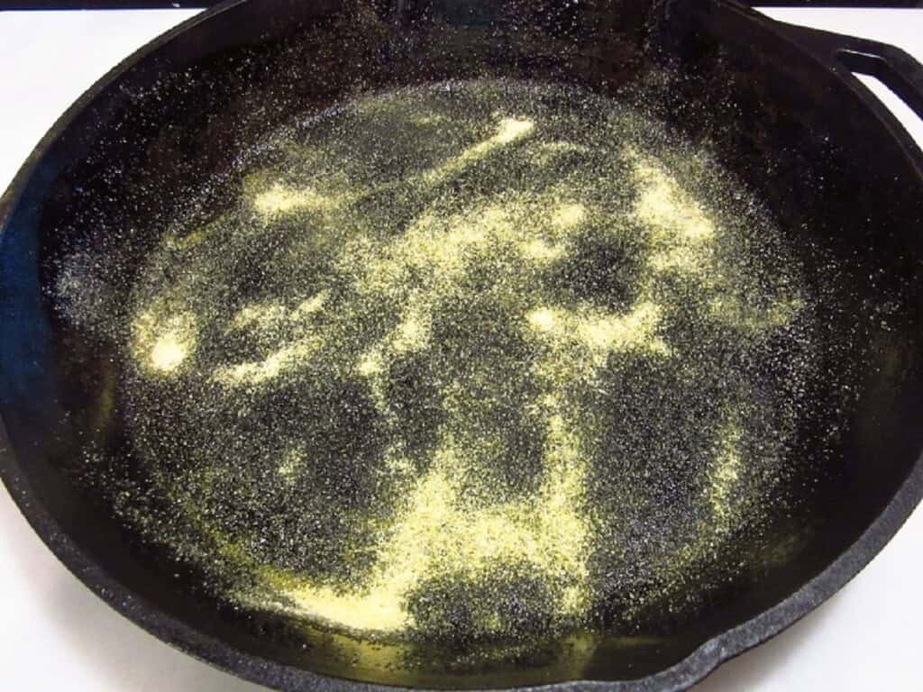 Corn meal sprinkled on the inside of a cast iron skillet.