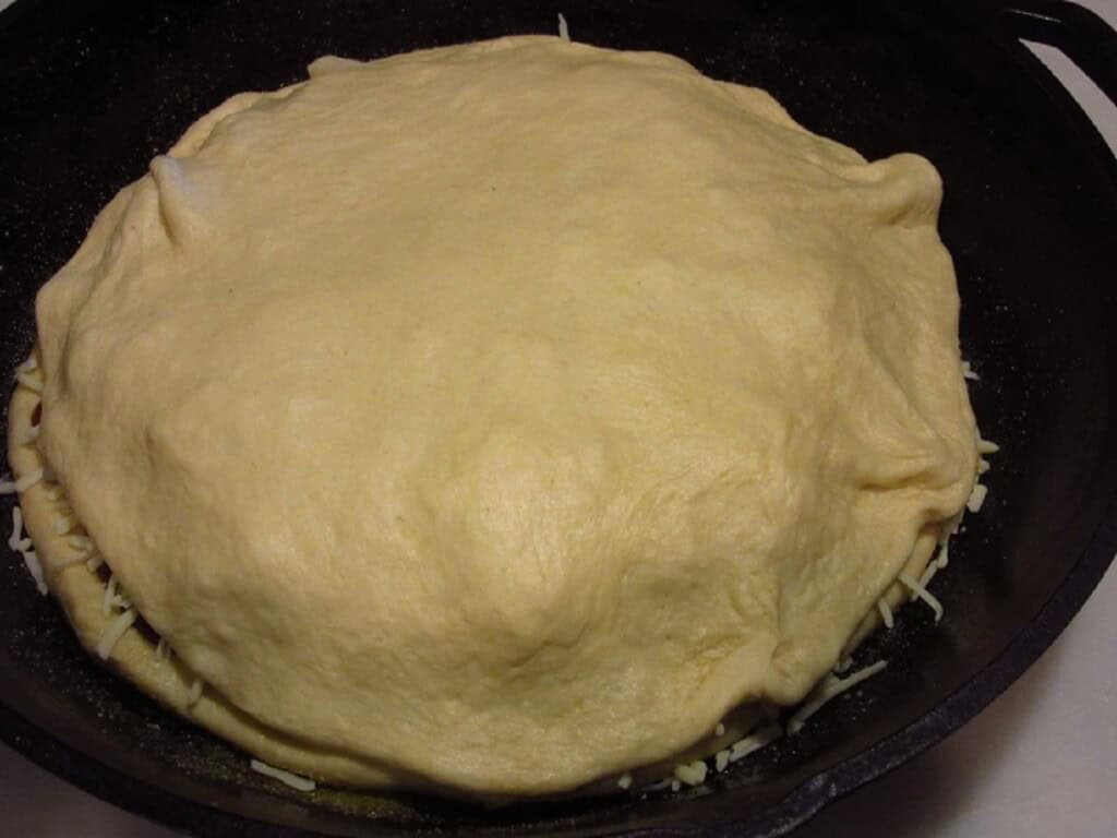 The top crust of an unbaked Hawaiian pizza.