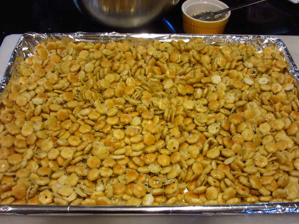 Everything seasoned oyster crackers spread out on a baking sheet covered with foil.