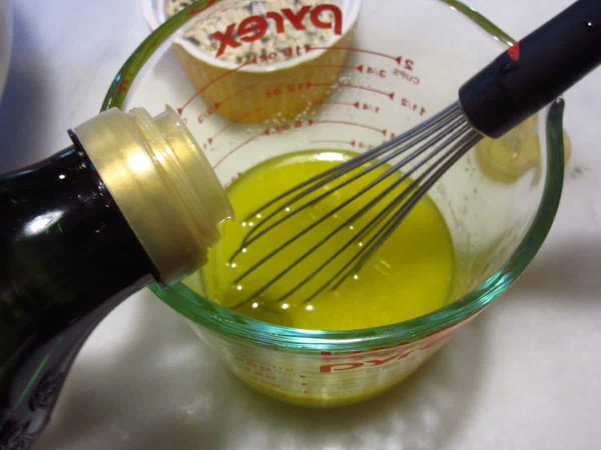 Olive oil being added to melted butter in a glass measuring cup.