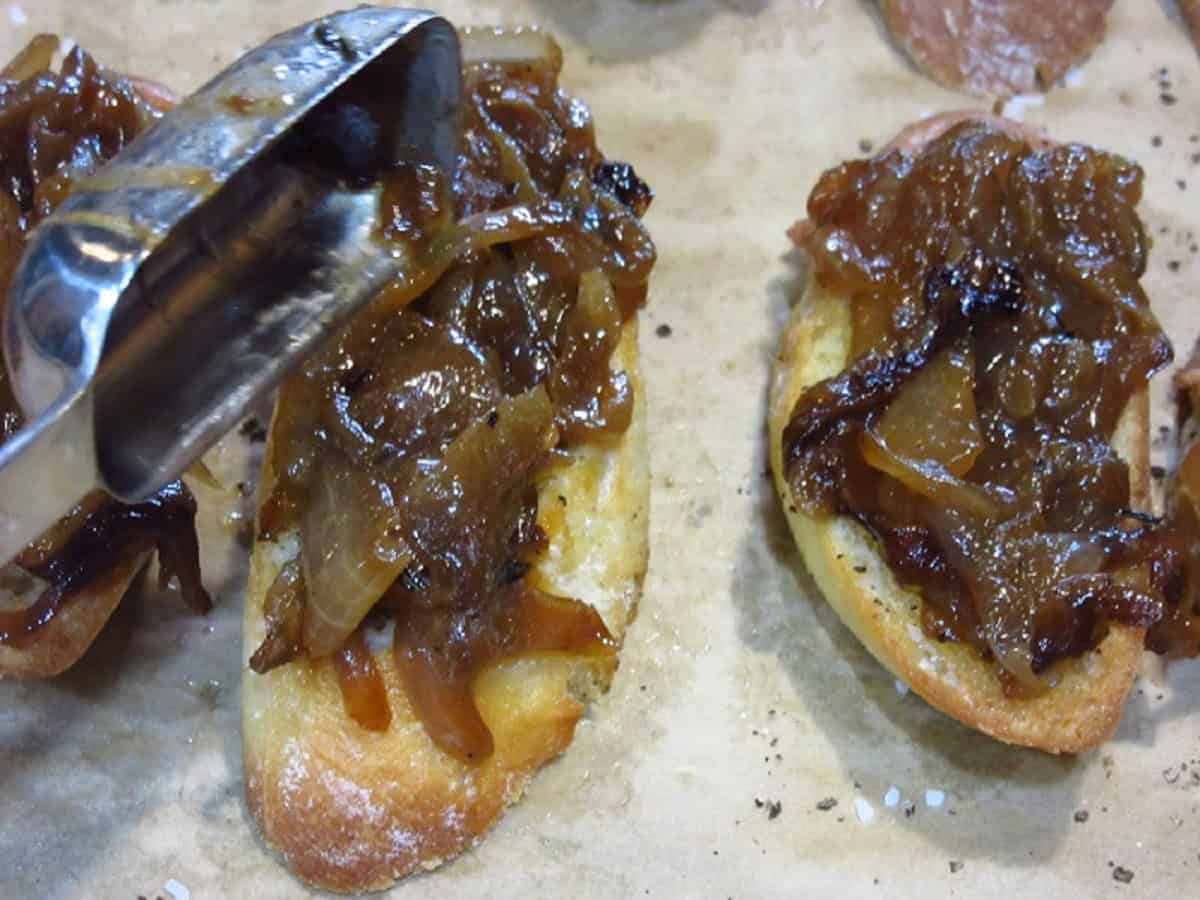 Topping toasted crostini slices with caramelized onions.