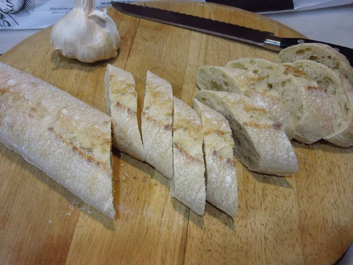 Diagonally sliced baguette on a cutting board.