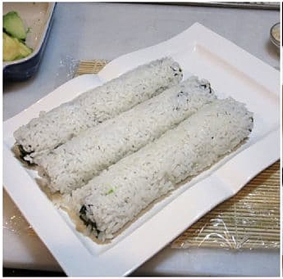 Two long sushi rolls before being sliced.