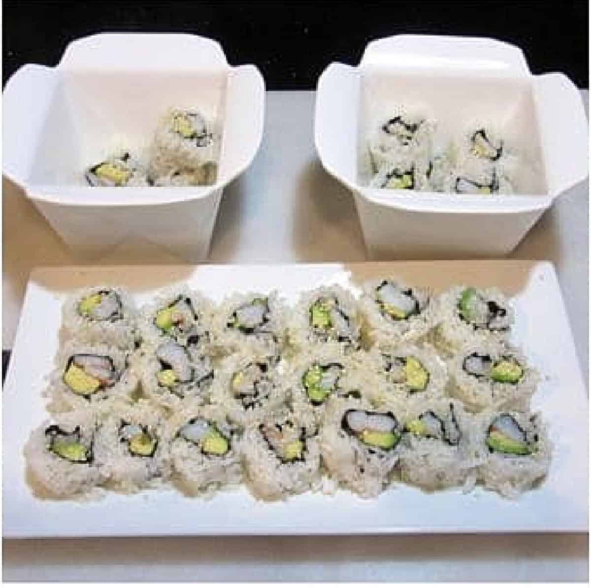 Two ceramic take out containers and a white plate filled with Avocado Shrimp Sushi Rolls.