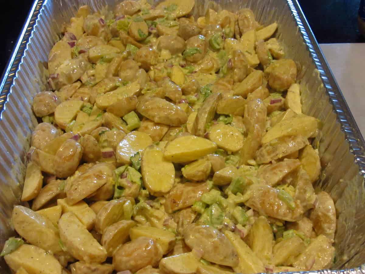 A tossed bunch of cut potatoes before baking to make a hot roasted potato salad.