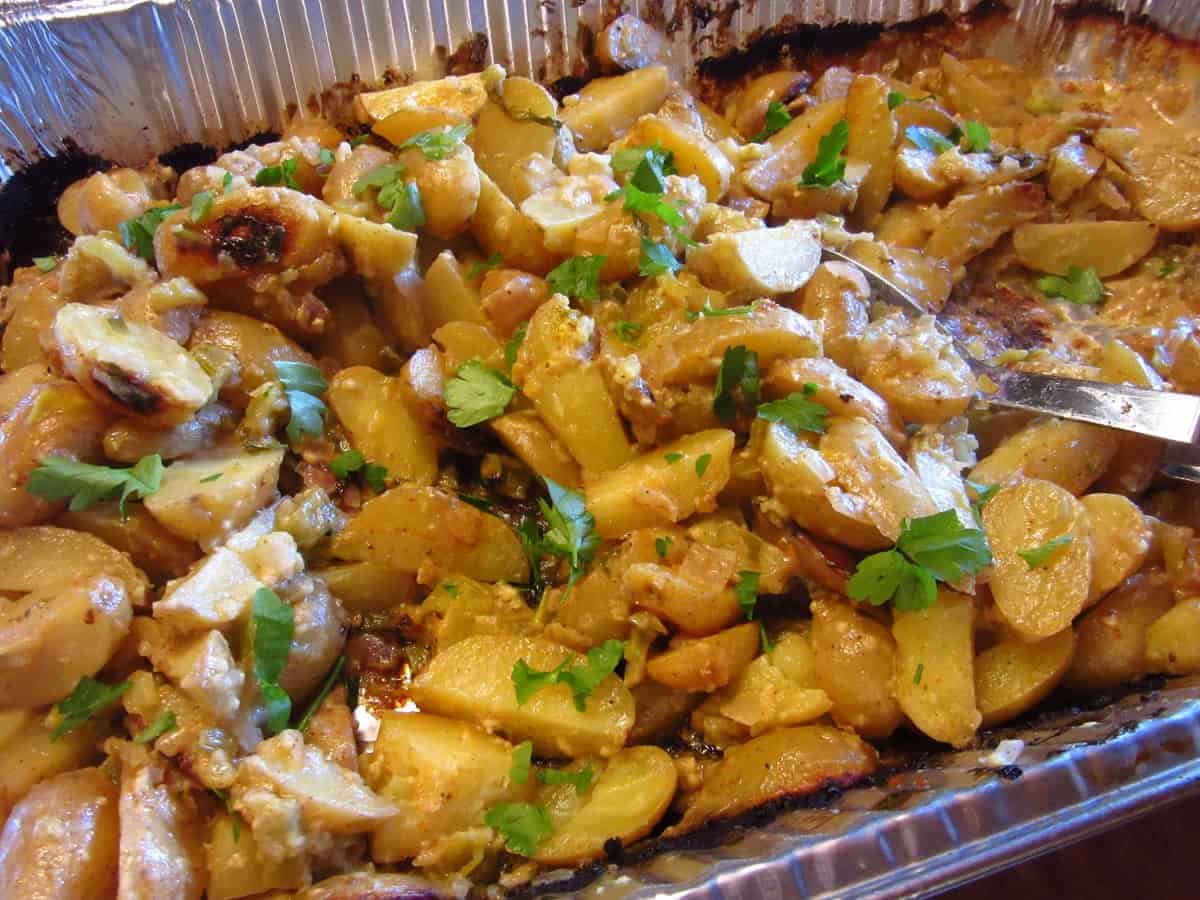 Hot roasted potato salad after cooking with a serving spoon.