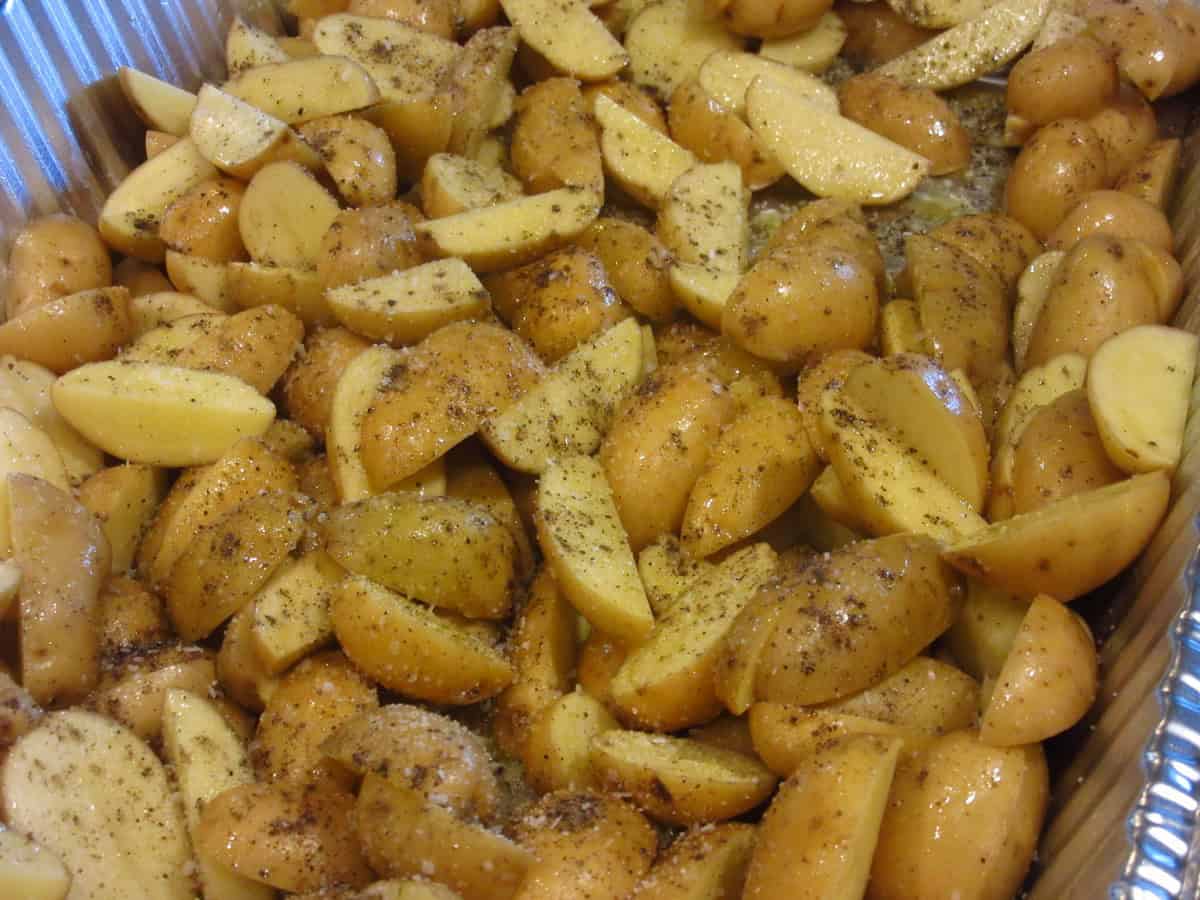 Seasoned cut up baby potatoes before cooking in a pan.