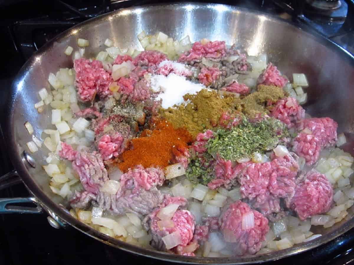 Browning ground beef, onions, and seasoning in a large skillet.