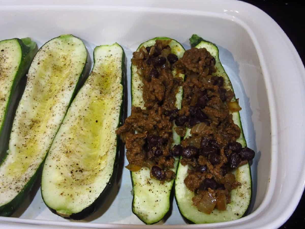 Ground beef taco mixture being added into zucchini boats.