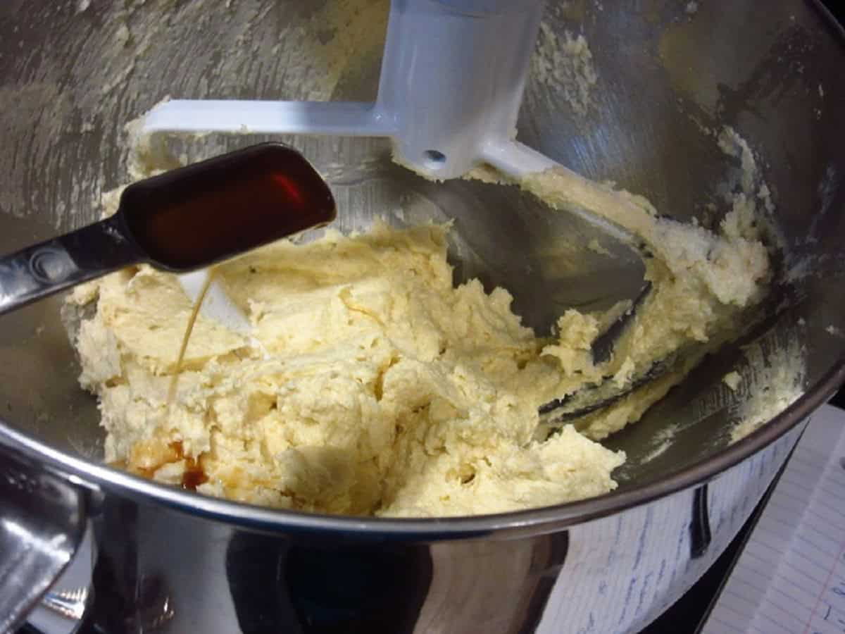 Vanilla extract being added to a stand mixer bowl.