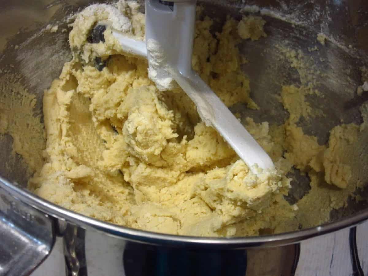 Cookie dough with a dough hook in a stand mixer bowl.