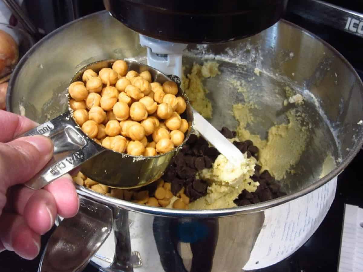 Caramel chips being added to a stand mixer bowl.