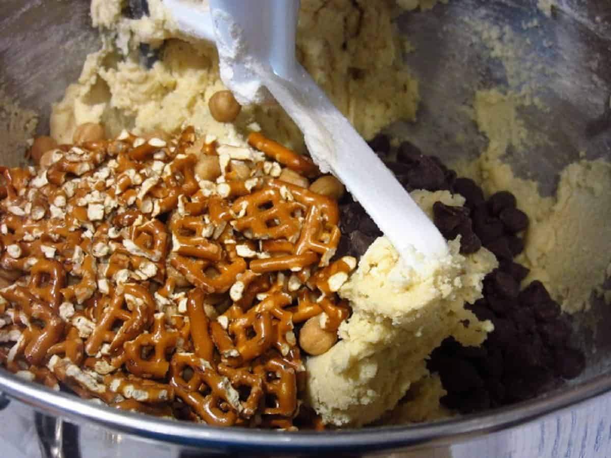Crushed pretzels in a cookie dough in a stand mixer bowl.