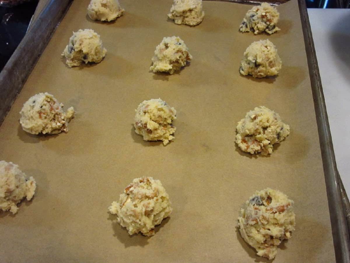 A bunch of scooped cookie dough on a baking sheet.