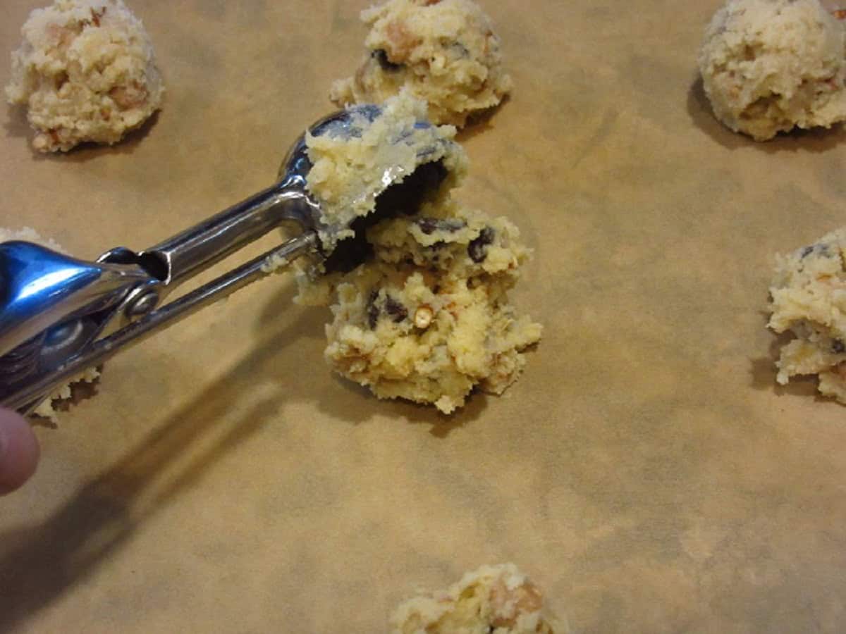 A cookie scoop scooping Take 5 Cookie dough onto parchment paper.