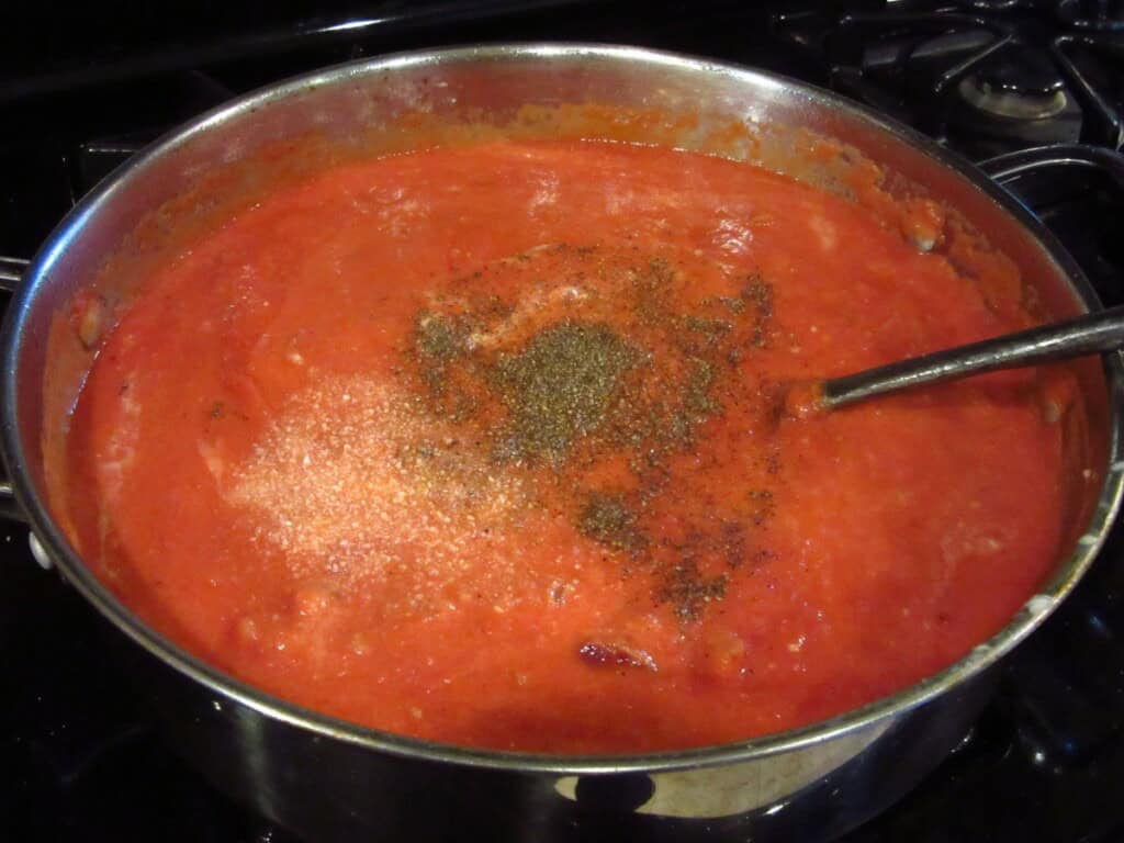 Salt and pepper in a mascarpone tomato sauce on the stovetop.
