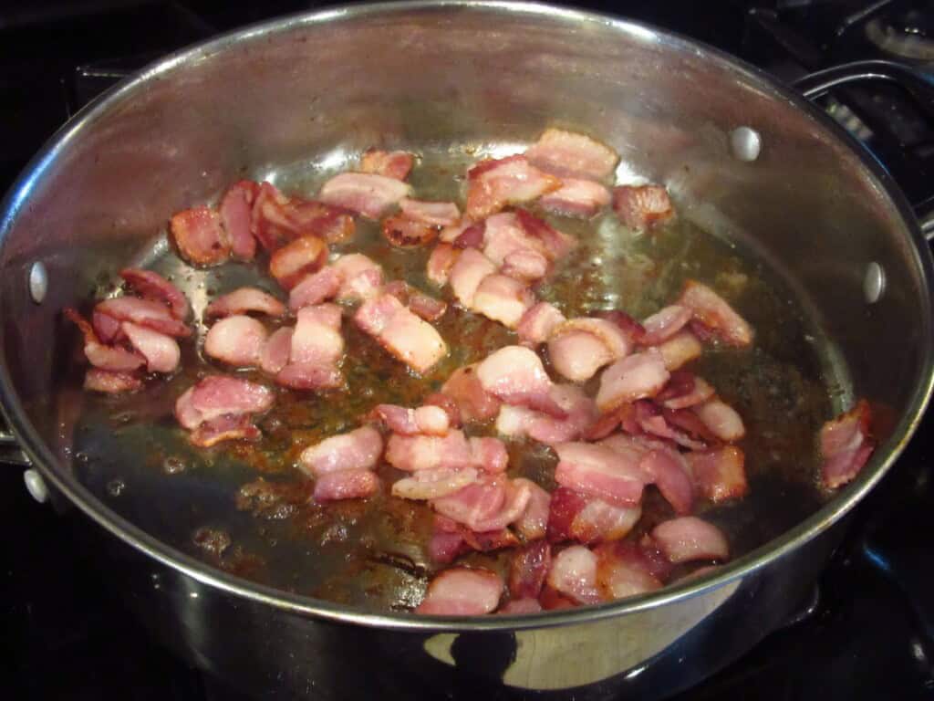 Cut up bacon browning in a large skillet.