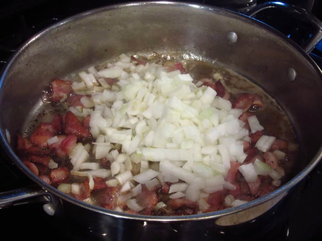 Chopped onions and bacon cooking in a large skillet.
