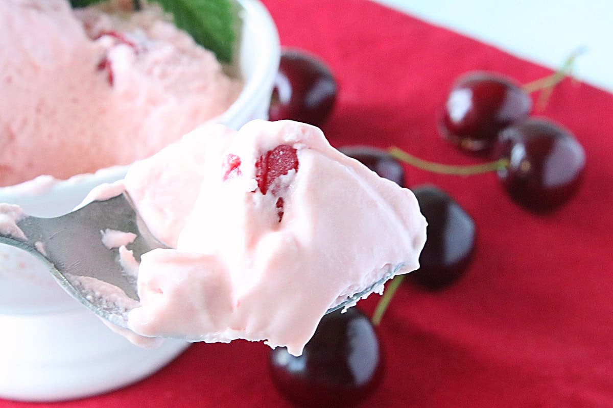 A spoonful of delicious looking pink cherry amaretto ice cream.