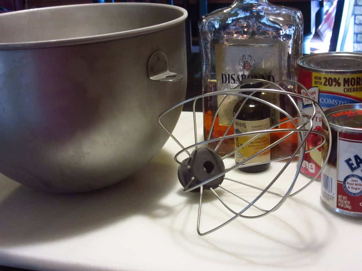 A ice cold stainless steel bowl and whisk on a countertop with ingredients.