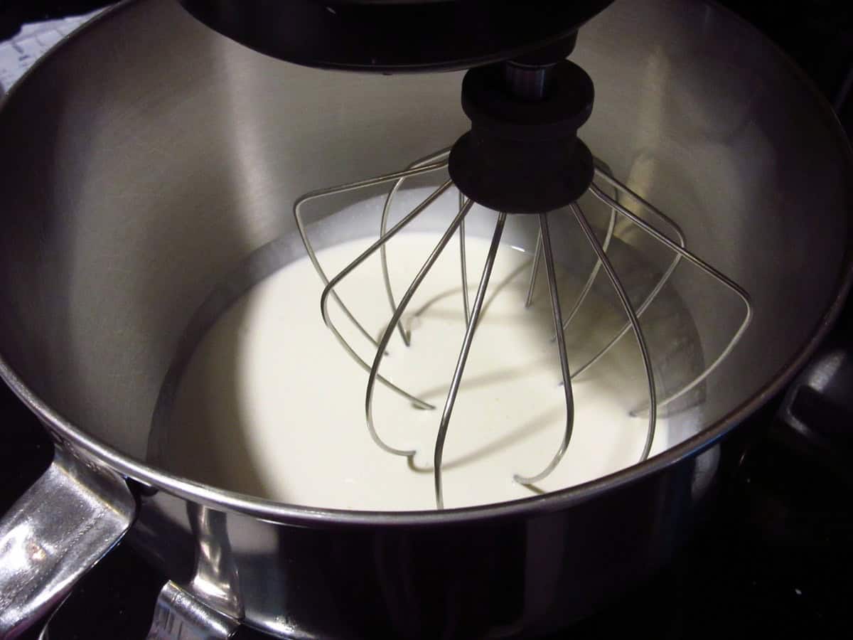 Heavy whipping cream in a stainless bowl along with a whisk.