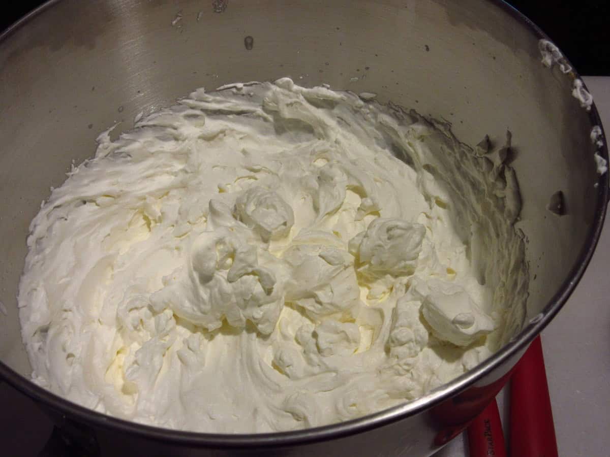 Whipped heavy cream in a stainless steel bowl.