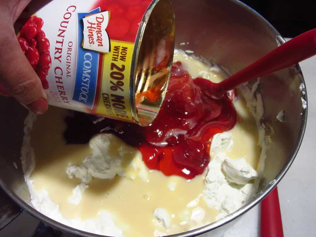 A can of cherry pie filling added to a stainless steel bowl for making no churn ice cream.