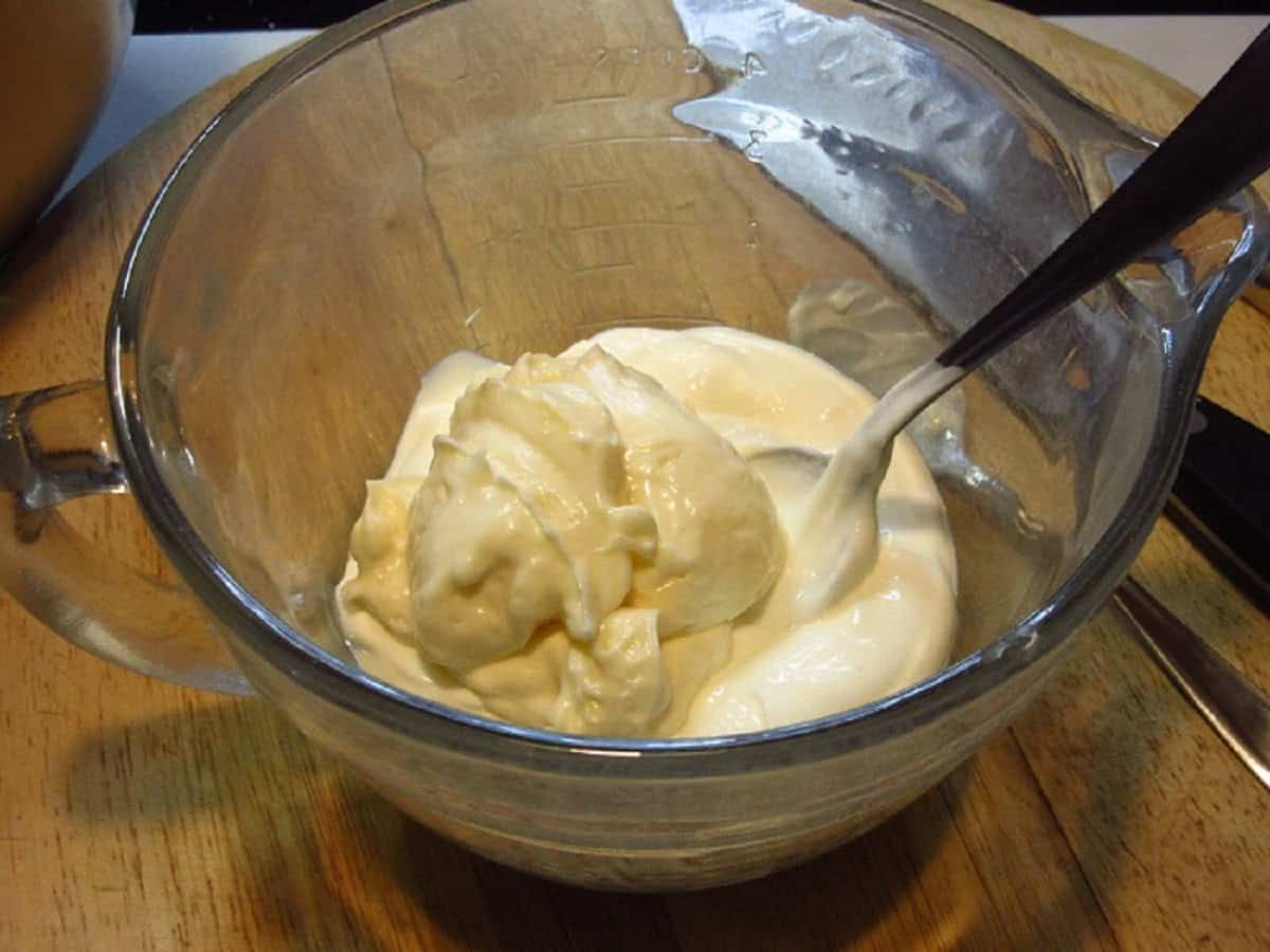 Mayonnaise and mustard in a glass measuring bowl.
