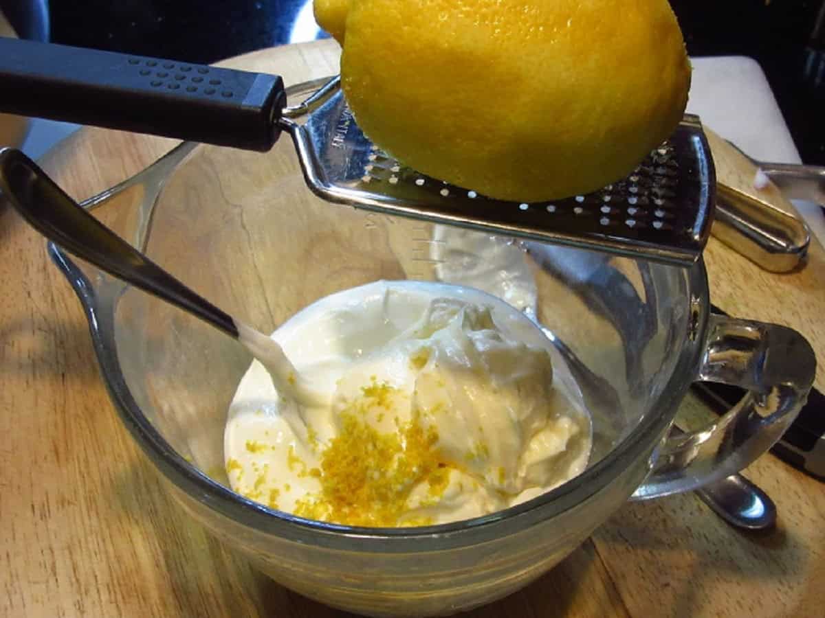 Fresh lemon zest being added to a cream sauce.