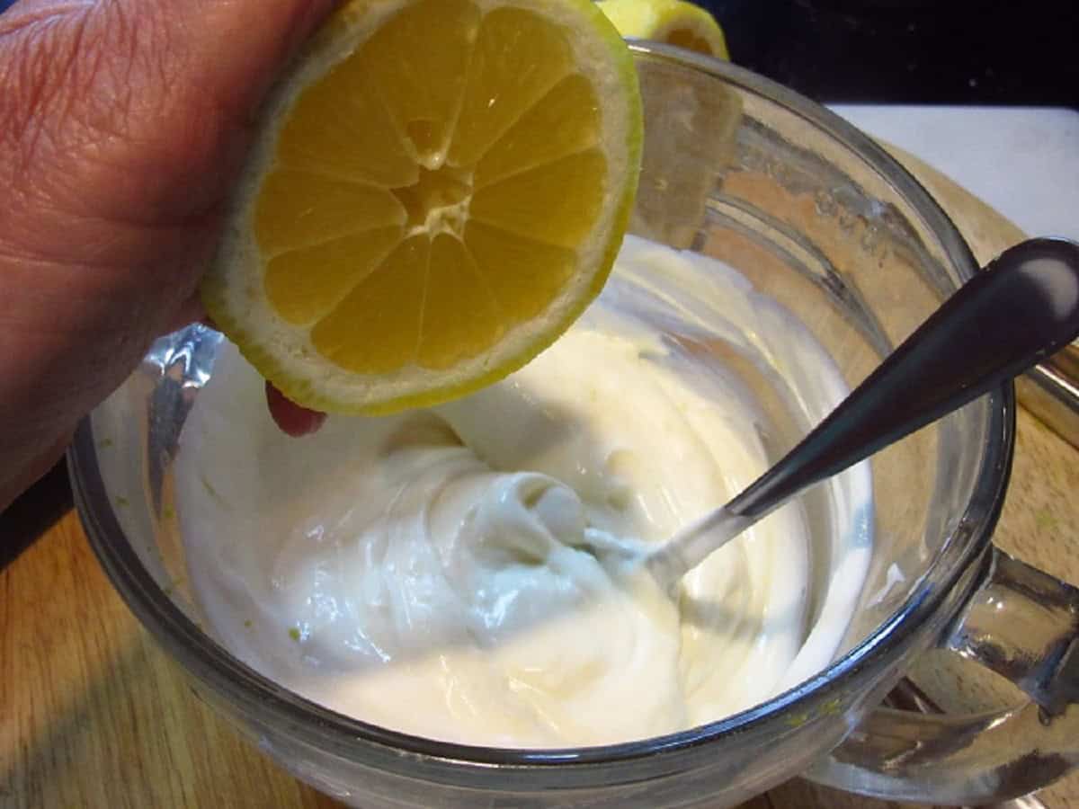 Fresh lemon being added to a creamy sauce.