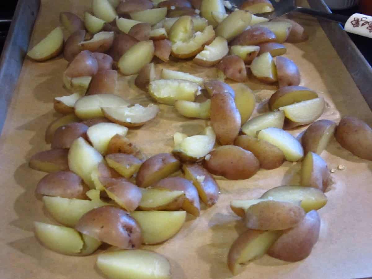 Cooked and cut red potatoes on a baking sheet.