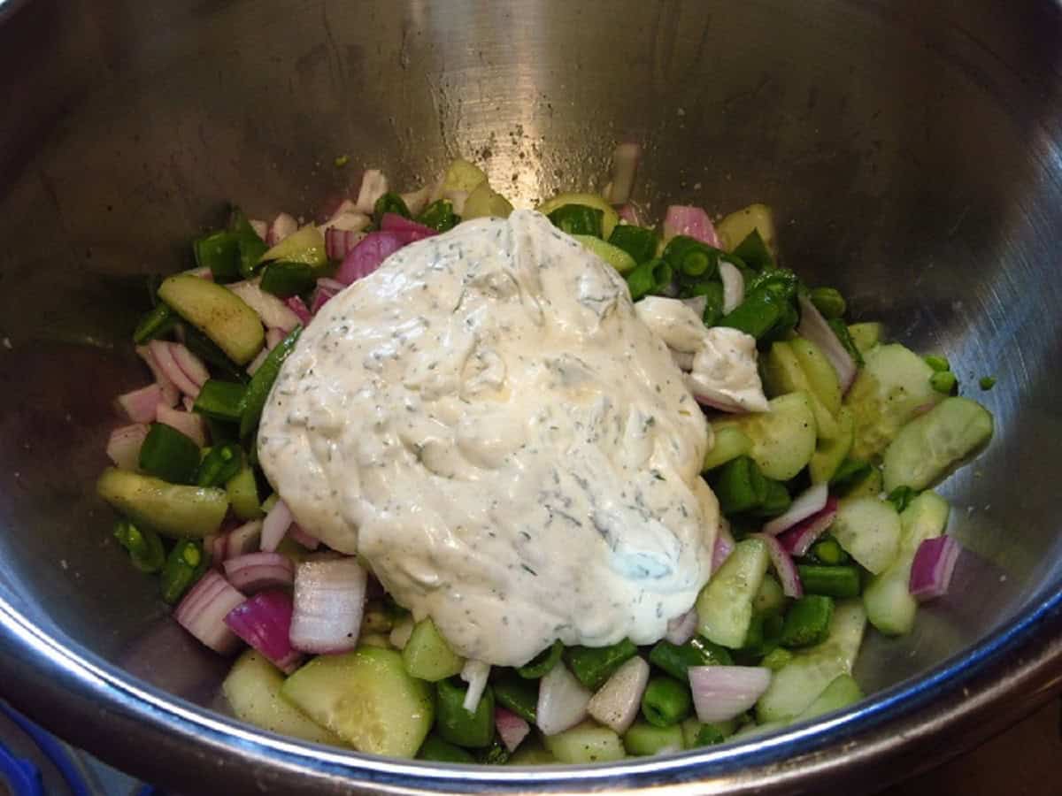 The mayo and dill sauce for a shrimp and cucumber salad in a bowl with the other ingredients.