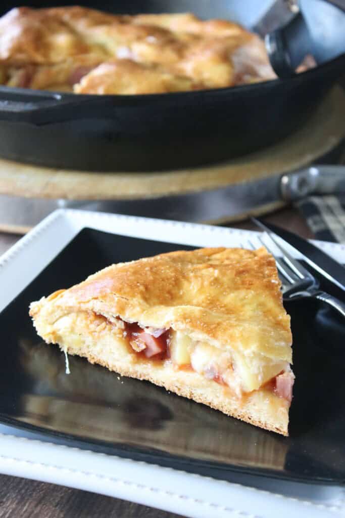 A slice of stuffed Hawaiian pizza on a square black plate.