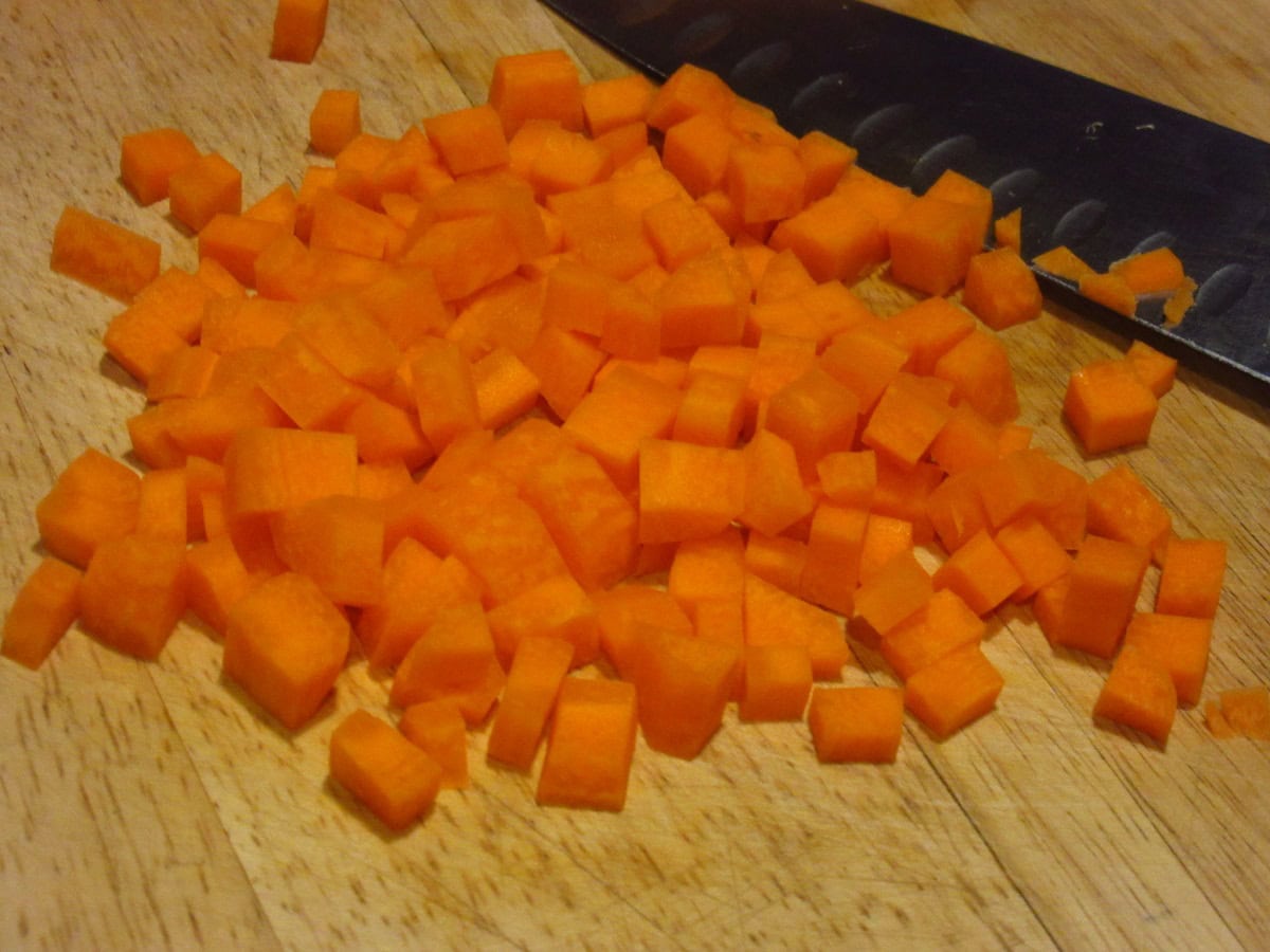 Diced carrots on a wooden cutting board.