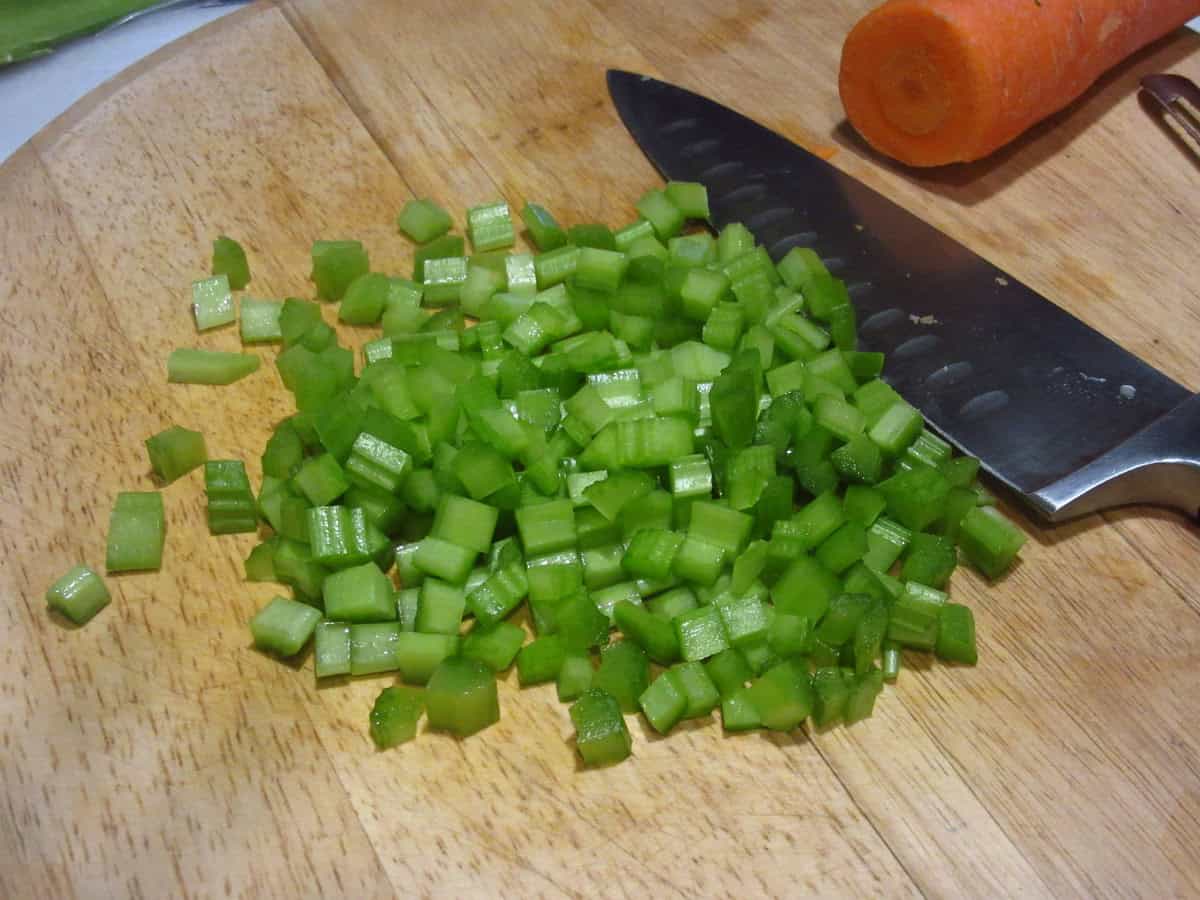 Diced celery on a wooden cutting board.