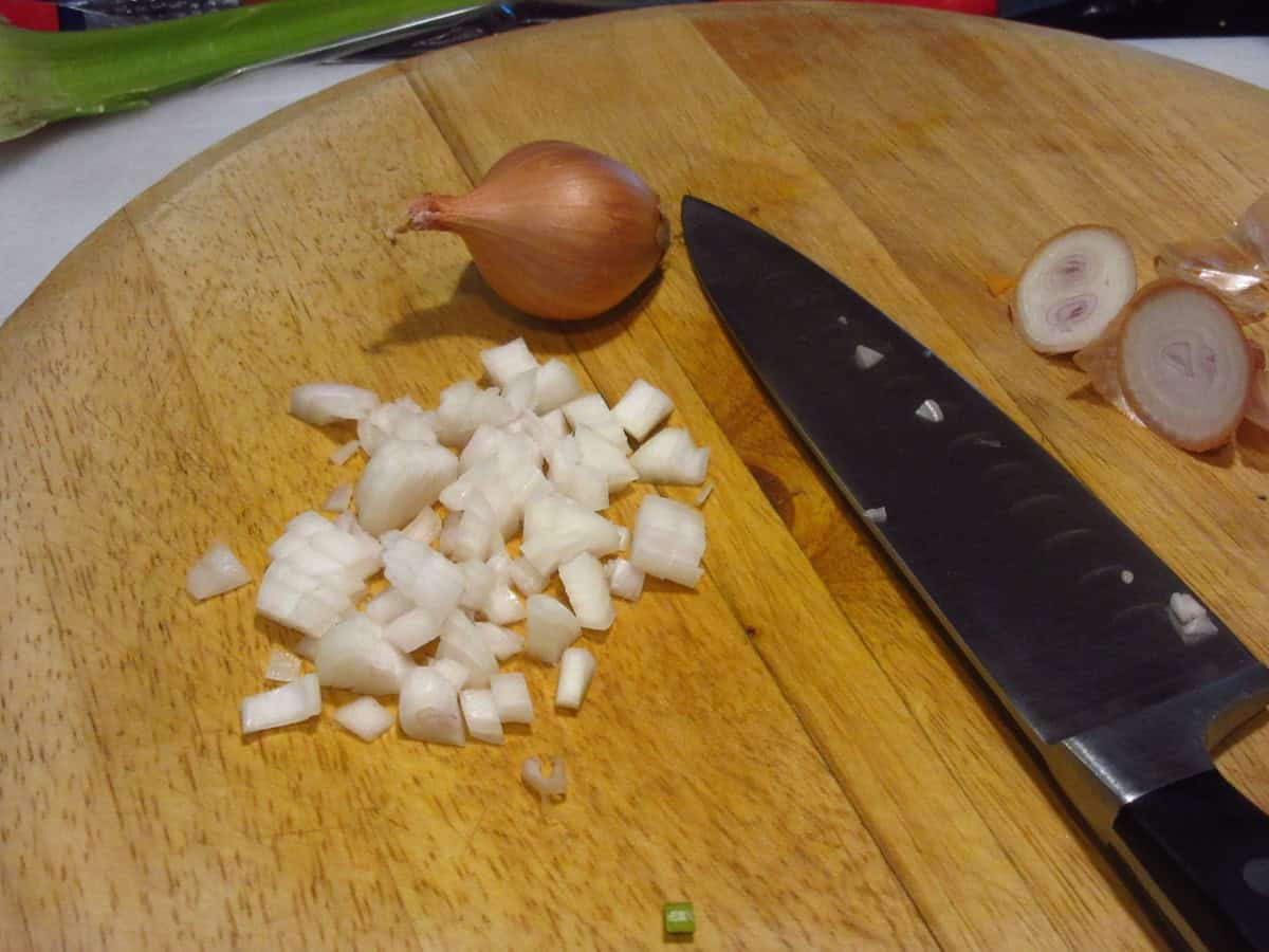 Minced shallots on a wooden cutting board.