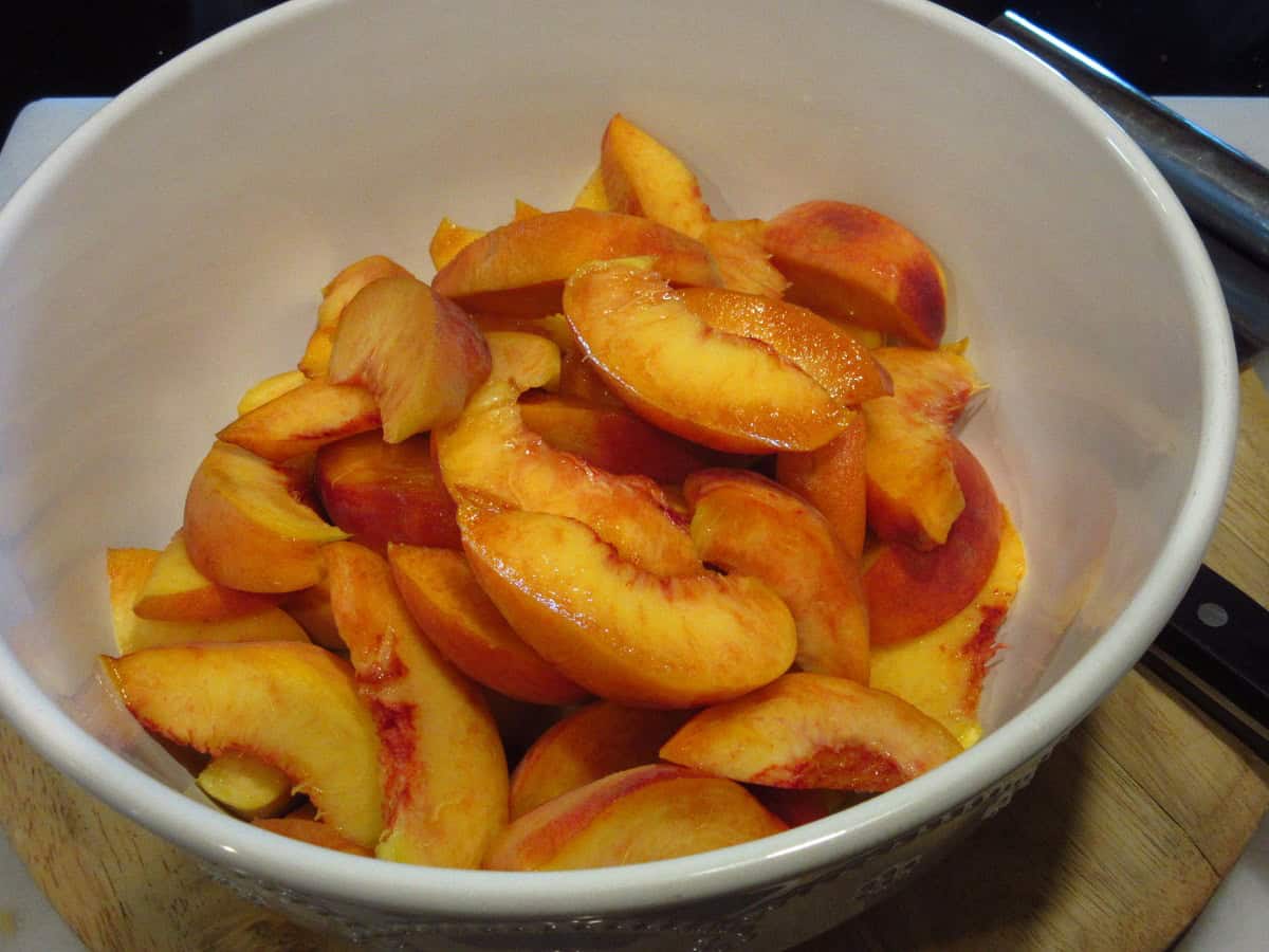Fresh peach slices in a large white bowl.