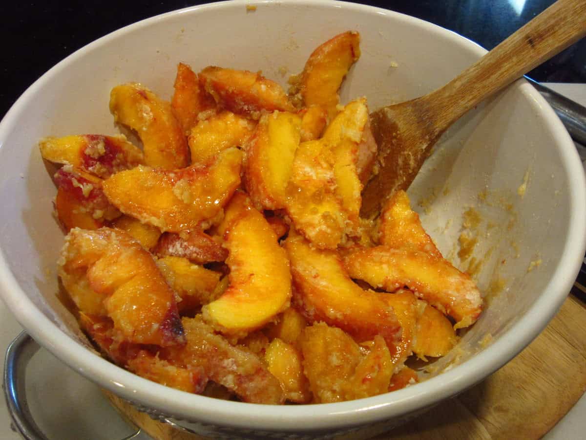 Fresh peaches mixed with other ingredients in a large bowl.