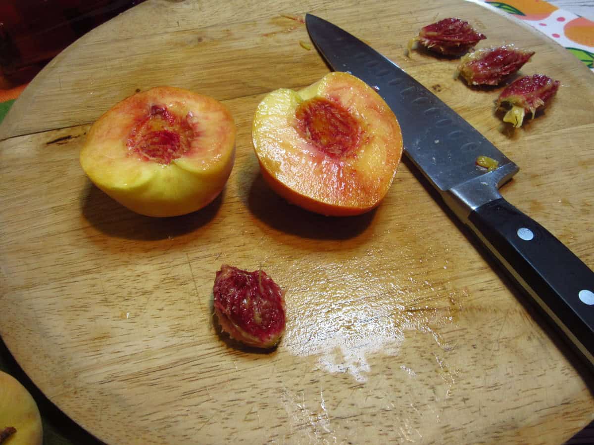A fresh peach on a cutting board with the pit taken out.