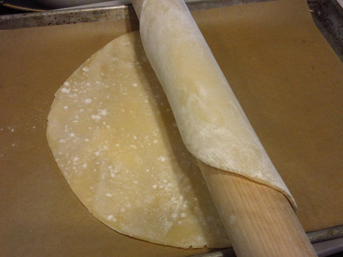 A rolling pie with a pie crust rolled on it for transfer.