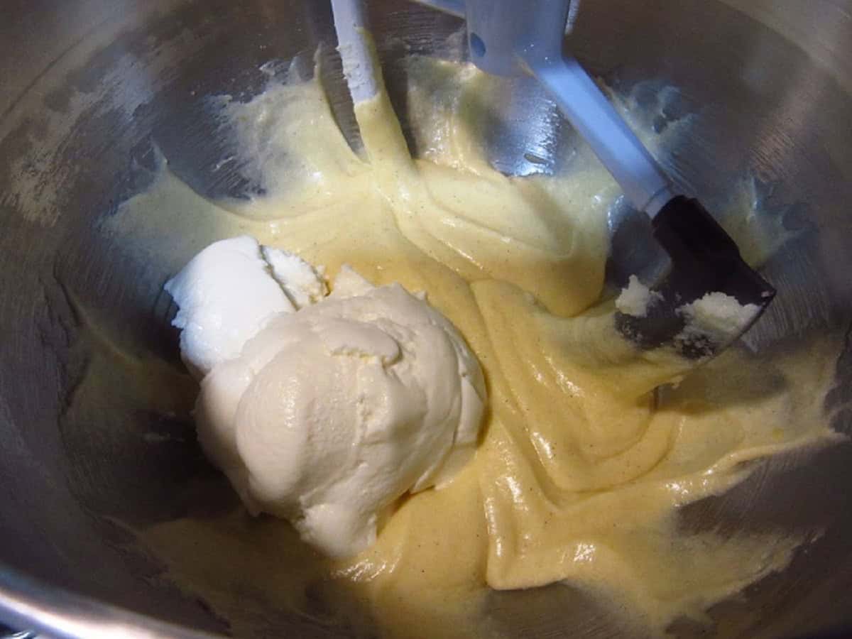 Creamy cookie batter in a stand mixer bowl with a blob of ricotta cheese.
